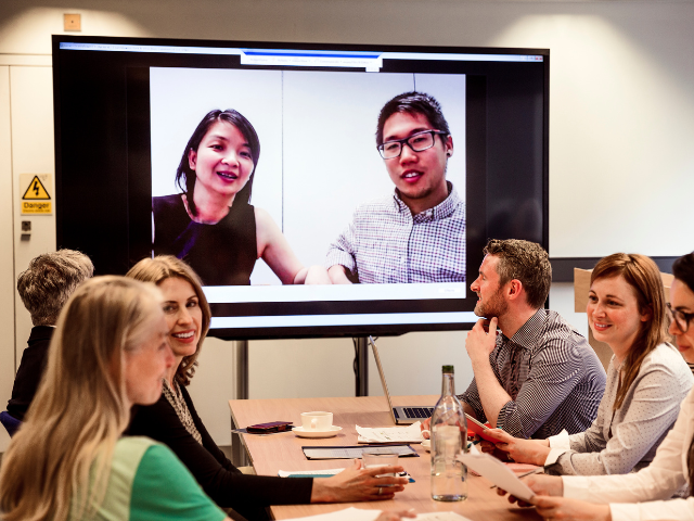 A group in a meeting with a certified interpreter on a screen facilitating multilingual dialogue