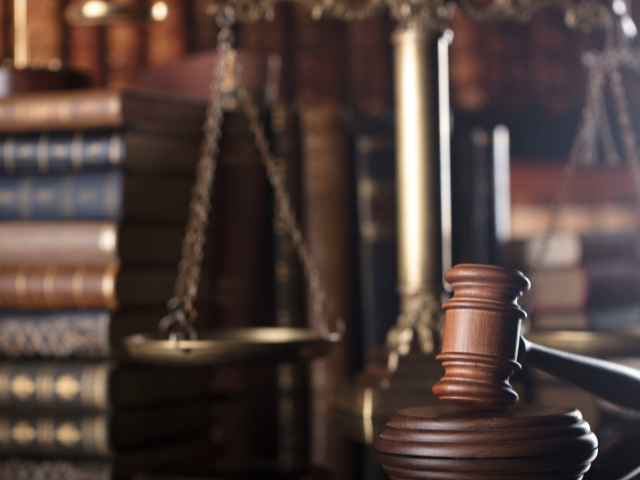 An image of a gavel and scales on a desk with law books in the backgroundpng